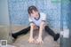 A woman in a white shirt and black stockings sitting on the floor.