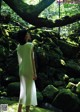 A woman in a white dress standing in the woods.