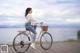 A woman riding a bike on a wooden dock by the water.