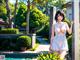 A woman in a white dress standing next to a pool.