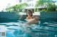 A woman in a bikini sitting in a swimming pool.