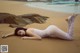 A woman laying on the beach in a white bodysuit.