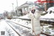 A woman in a white coat standing on a train track.