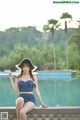 A woman in a blue and white polka dot bikini sitting by a pool.