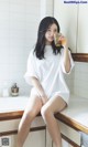 A woman sitting on a counter holding a glass of orange juice.