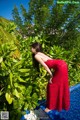 A woman in a red dress standing next to a swimming pool.