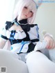 A woman in a maid outfit sitting on a bed.