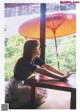 A woman sitting at a table with an umbrella.