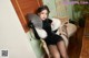 A woman in a black dress sitting on a chair holding a fan.