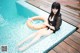 A woman sitting on the edge of a swimming pool with an inflatable ring.