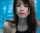 A woman in a black bathing suit standing in a pool.