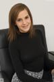 A woman sitting in a black chair smiling at the camera.