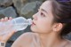 A woman drinking water from a plastic bottle.